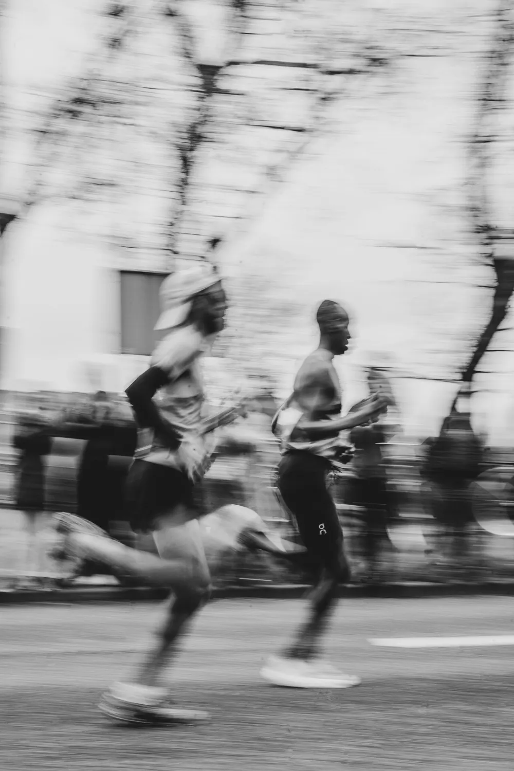 Two runners mid-stride, panned so the street behind them blurs into a current.